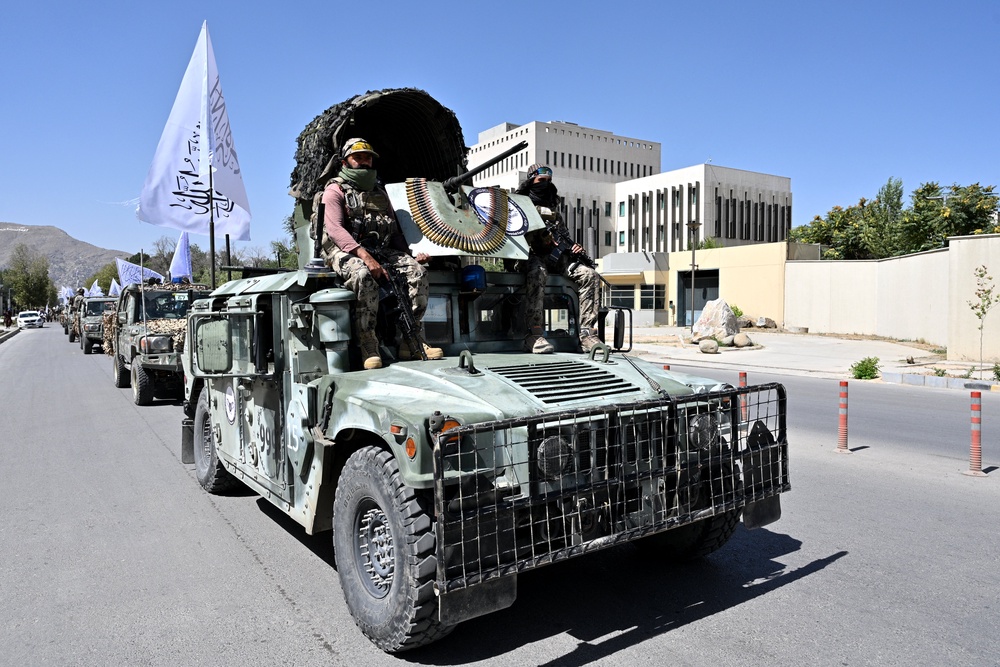 A convoy of Taliban security personnel take part in a parade in front of the former US Embassy building (back) in Kabul (AFP/Getty)
