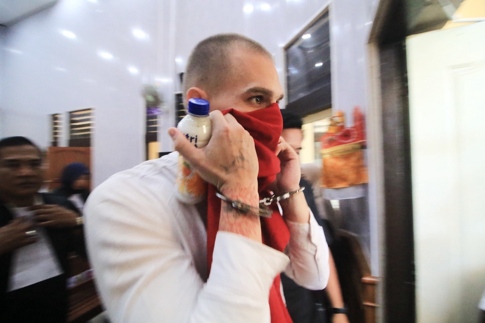 Swiss tourist Luzian Andrin Zgraggen who is accused of insulting the Balinese Hinduism's sacred Day of Silence in social media posts, covers his face as he leaves the courtroom after his sentencing hearing at the district court in Denpasar, Bali, Indonesia (AP)