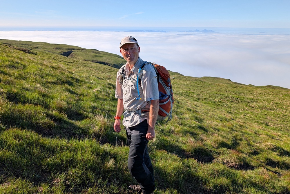 Hiking guide Tony McLean with a cloud inversion in the background and the Paps of Jura poking out (Julia Clarke)
