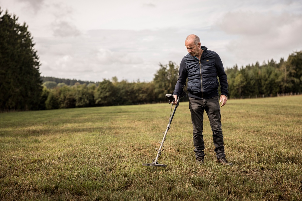 Bernard Collard runs a metal detector over a field in the Elsenborn area of Krinkelt, Belgium (AP)