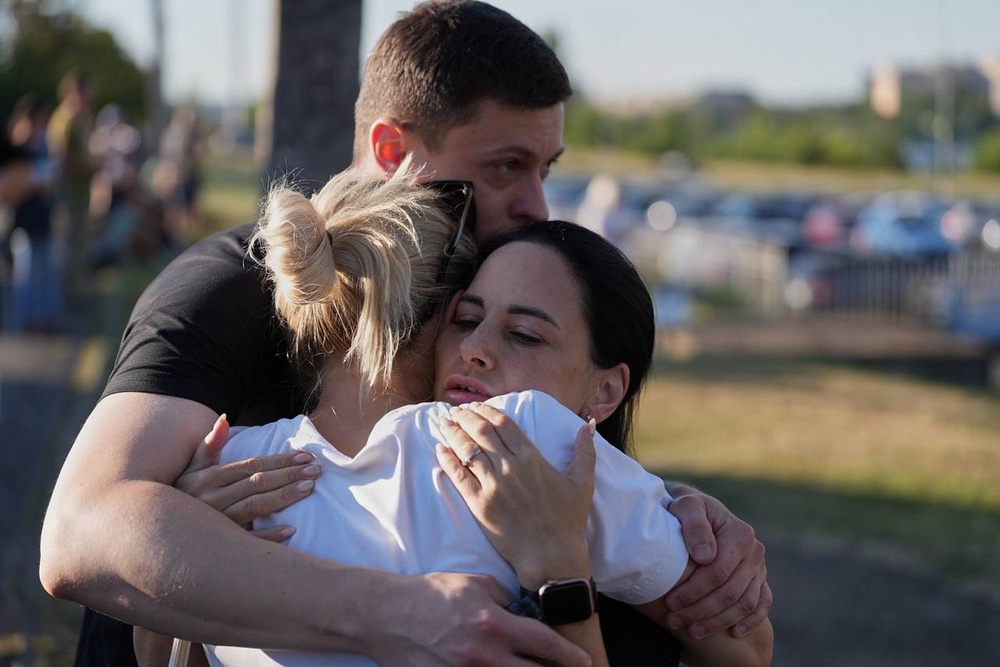 People embrace each other near a burning shopping mall following a Russian drone attack in Kryvyi Rih, Ukraine (AP)