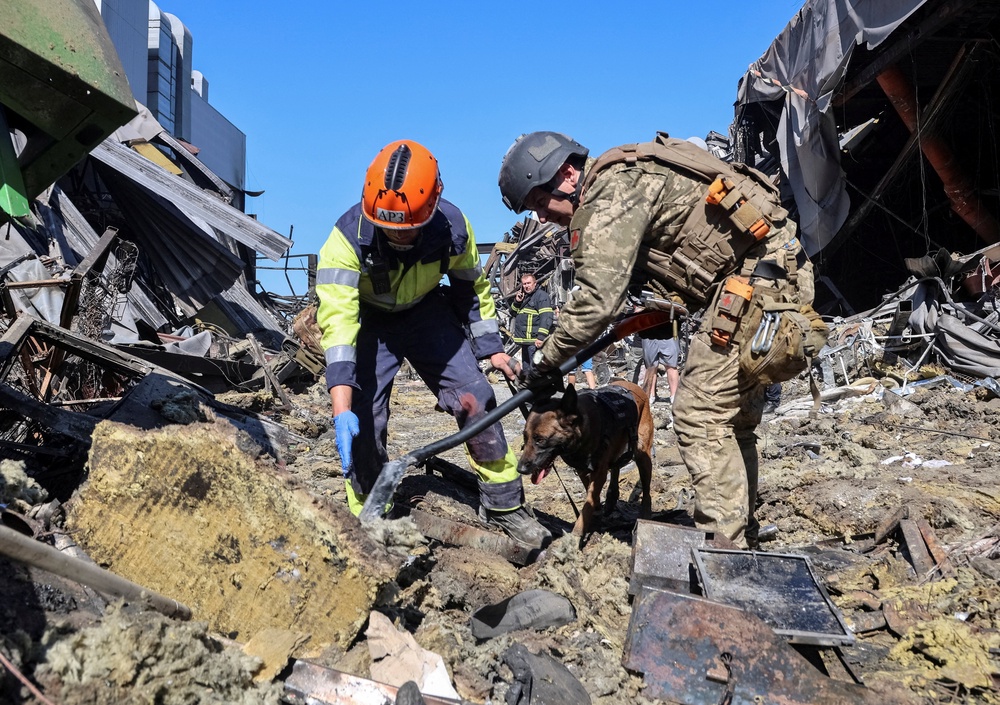 Rescuers with a dog work at a site of a shopping centre destroyed by yesterday's Russian drone attack (Reuters)
