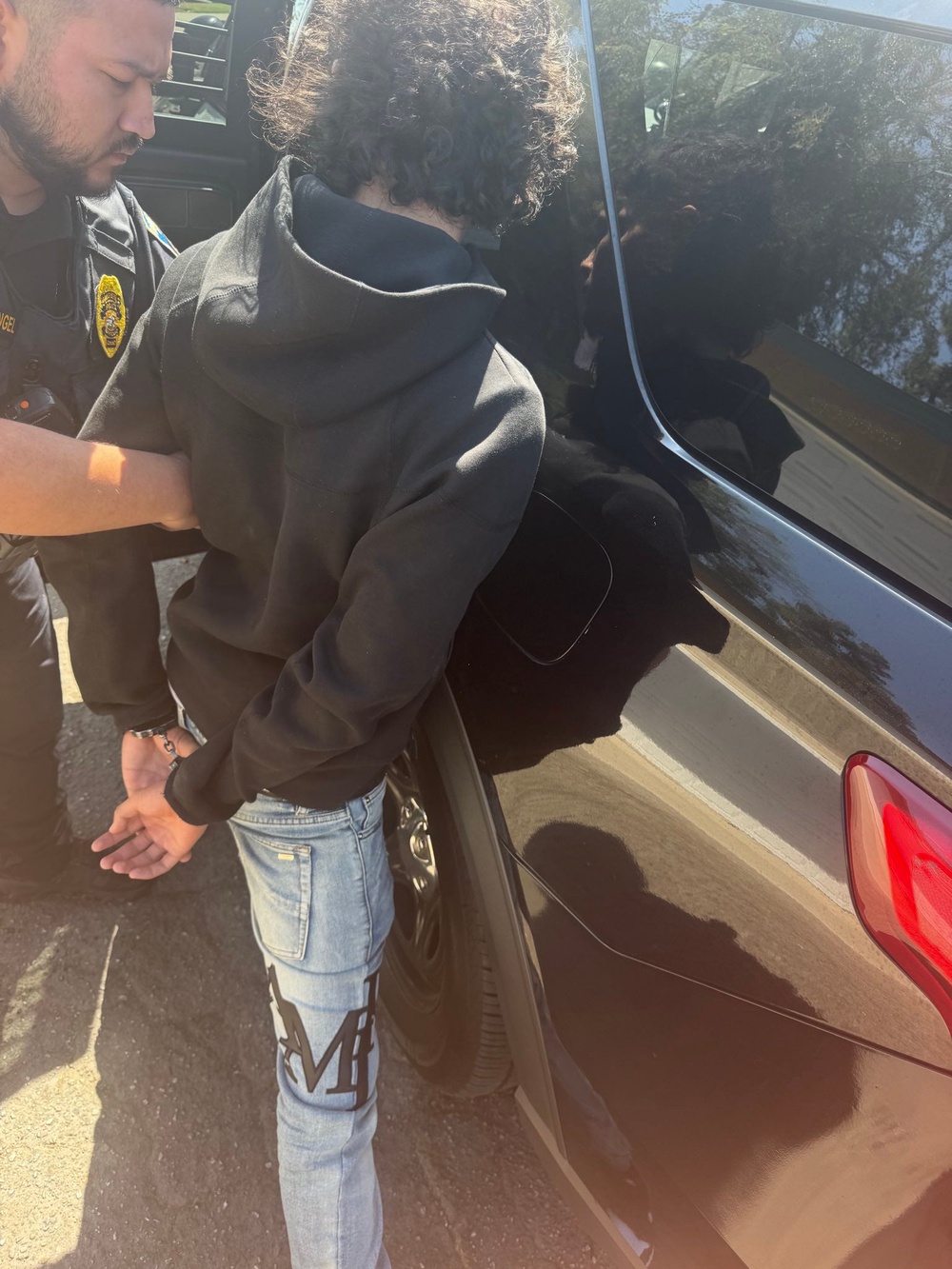 A police officer leads the handcuffed 15-year-old suspect to a vehicle (Bakersfield Police Department)