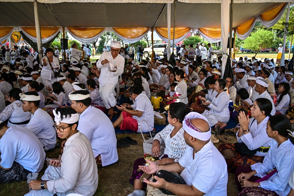 A Hindu priest sprinkles holy water over devotees during the Melasti ceremony prayer at Kenjeran beach in Surabaya on 14 March 2026 (AFP/Getty)