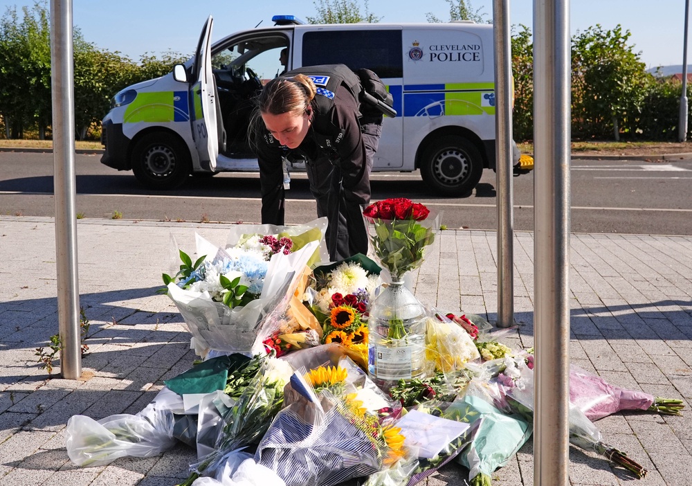 A police officer leaves flowers at the Cleveland Police HQ Memorial Garden in Middlesbrough, following the line-of-duty deaths of PC Matthew Blades and PC Tom Clough (PA)