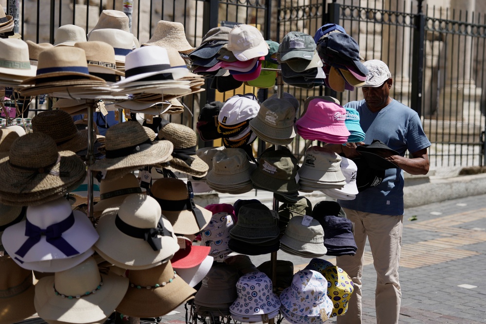 A tourist chooses a hat from a souvenir shop in Athens, Greece, Wednesday, Aug. 12, 2026. (AP Photo/Thanassis Stavrakis) (AP)