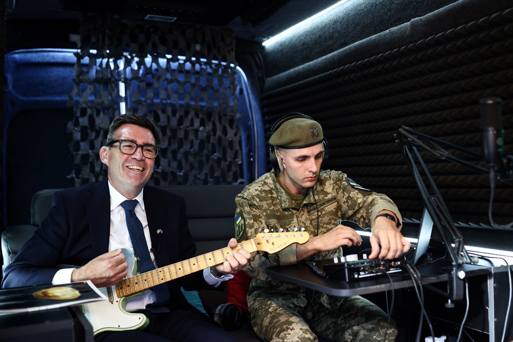 Andy Burnham plays the guitar in the mobile recording studio of the military and artistic unit who perform on the front line (PA)