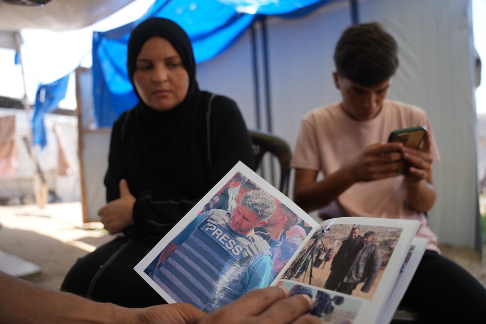 Family members of Palestinian journalist Hussam al-Masri, who worked as a freelance journalist for Reuters and was killed in an Israeli airstrike targeting the Nasser Hospital building in Khan Younis on Aug. 25, 2025, look at his photos in Khan Younis, southern Gaza Strip, Aug. 16, 2026. (AP Photo/Abdel Kareem Hana) (Copyright 2026 The Associated Press. All rights reserved.)