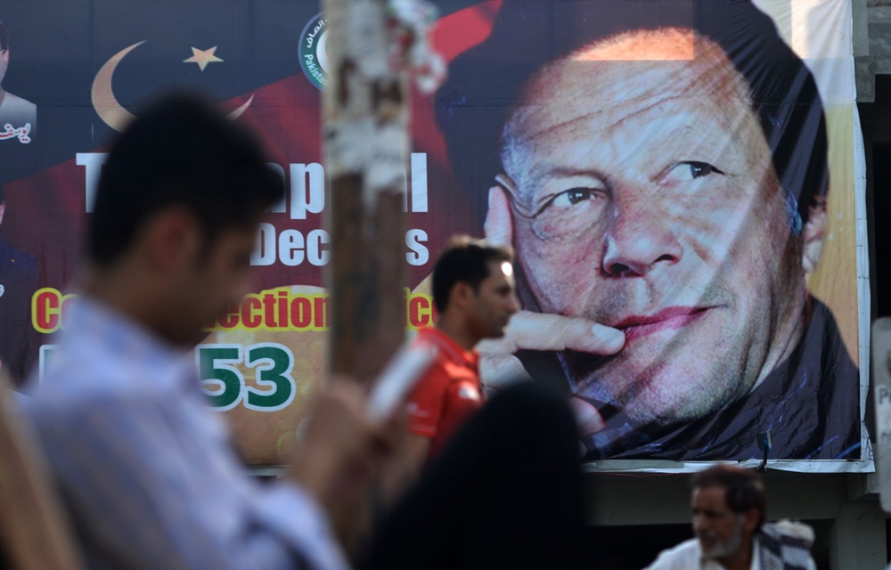 Pakistani men sit near a poster of Pakistan's cricketer-turned politician Imran Khan in Islamabad (AFP via Getty Images)