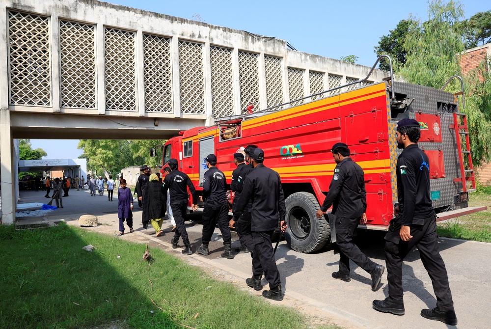 Members of Anti-Terrorist Squad move past a fire engine following a deadly fire at the Pakistan Institute of Medical Sciences (PIMS) hospital in Islamabad, Pakistan, 26 August 2026 (Reuters)