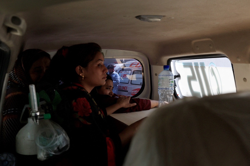 Javeria, mother of a newborn victim, holds onto a coffin containing the body of her newborn inside an ambulance following a deadly fire at the Pakistan Institute of Medical Sciences (PIMS) (Reuters)