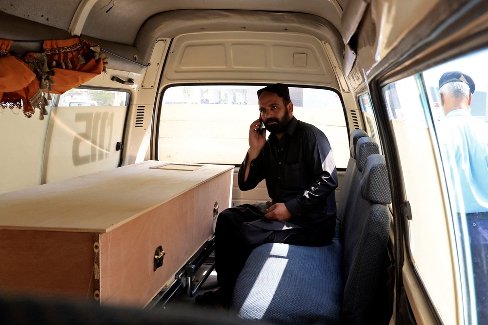 A man speaks on this mobile phone next to a coffin containing the body of newborn victim inside an ambulance (Reuters)