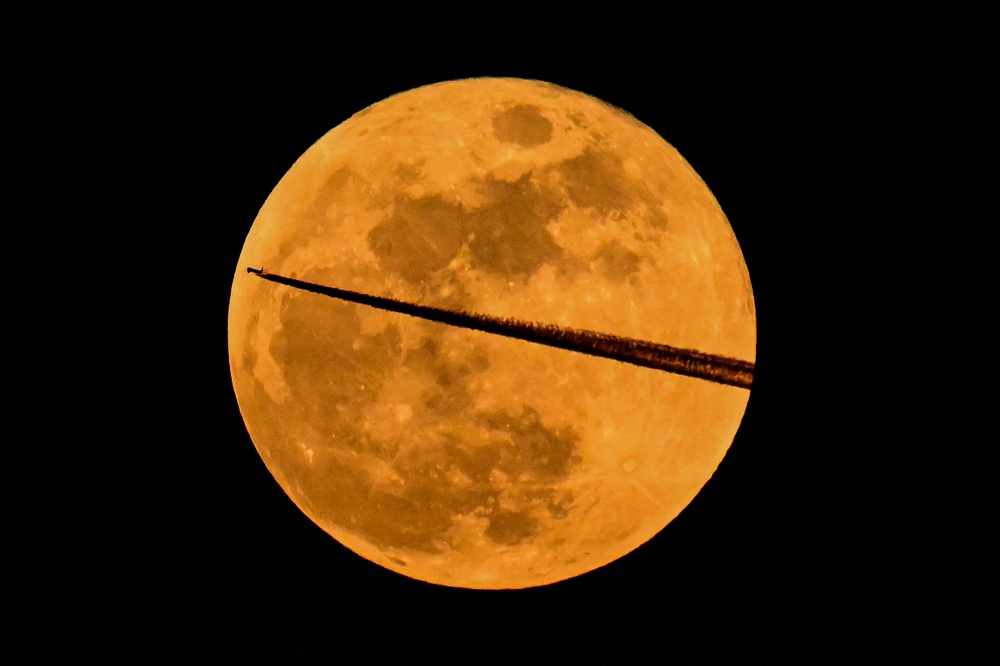 A Bulgaria Air Airbus A220-100 aircraft flies past March full moon, also known as 
