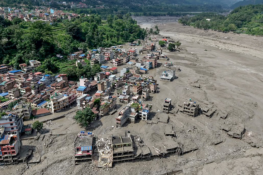 Houses lie partially submerged in muddy water along a riverside after flash floods at Trishuli Bazar in Nepal's Nuwakot district on August 26, 2026 (AFP/Getty)