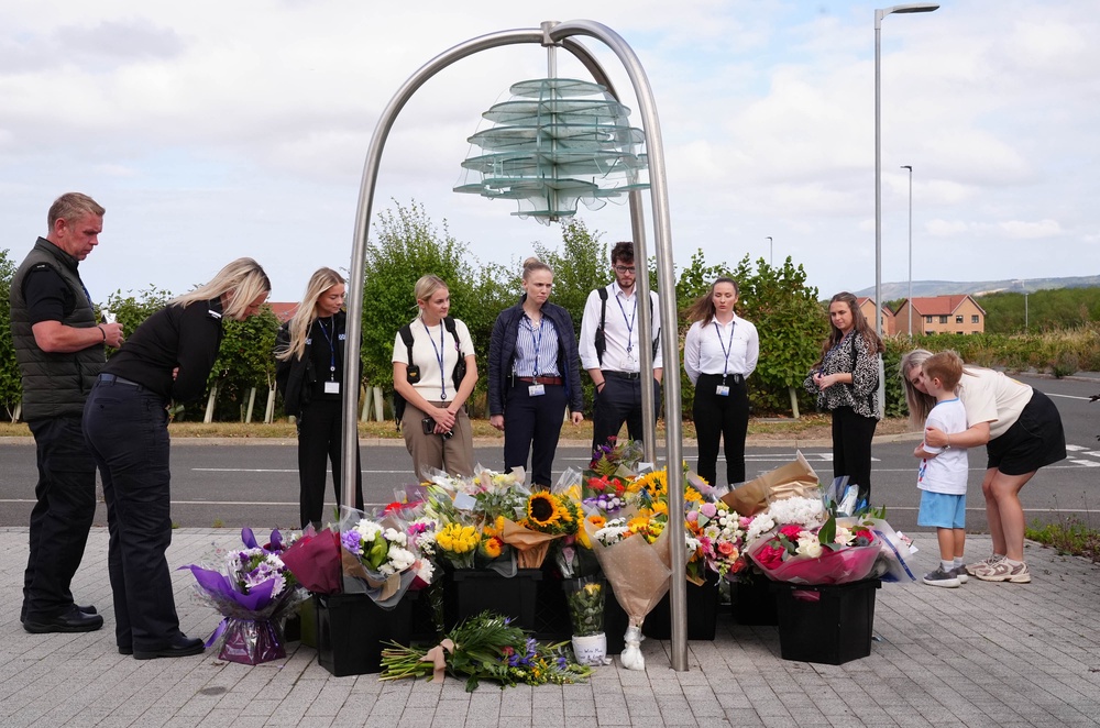 Police officers and members of the public look at flowers at the Cleveland Police HQ in Middlesbrough (Owen Humphreys/PA) (PA Wire)