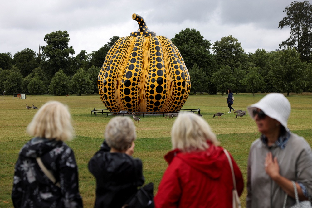 People look at Japanese artist Yayoi Kusama's sculpture 'Pumpkin' in Kensington Palace Gardens in London in 2024 (Reuters)