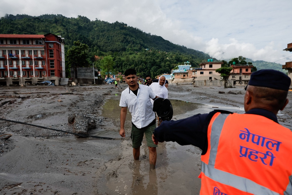 People wade through muddy waters following devastating floods, in Trishuli in Nuwakot district, Nepal, August 27, 2026 (Reuters)