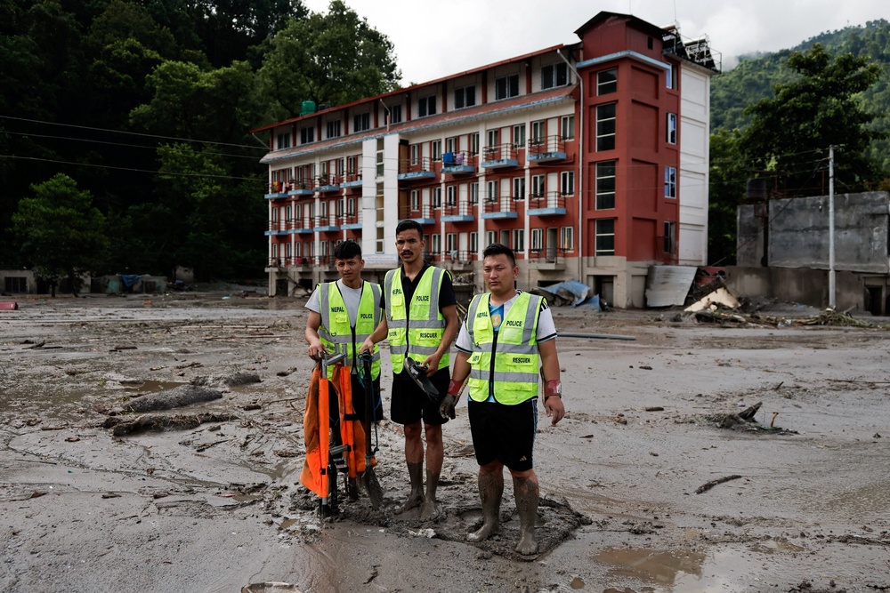 Members of a rescue team stand amid mud and debris following devastating floods, in Trishuli in Nuwakot district, Nepal, 27 August 2026 (Reuters)