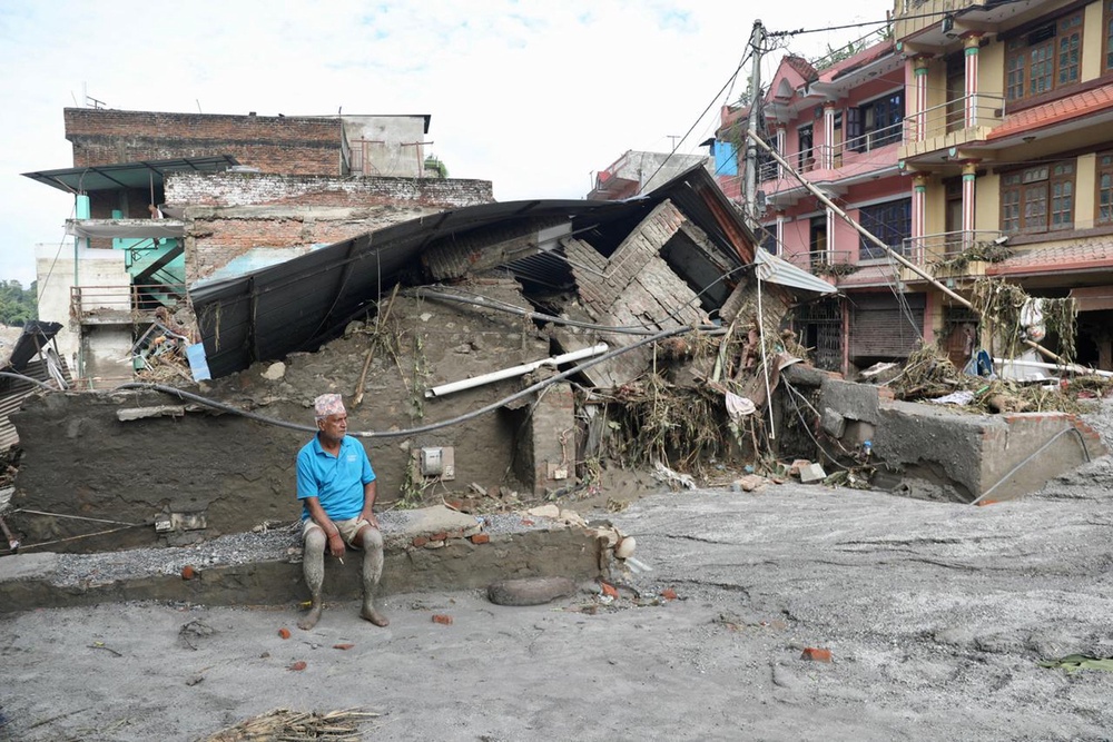 A local resident sits near a collapsed house lying deluged in sludge after flash floods at Devighat, Bidur Municipality in Nepal's Nuwakot district (AFP/Getty)