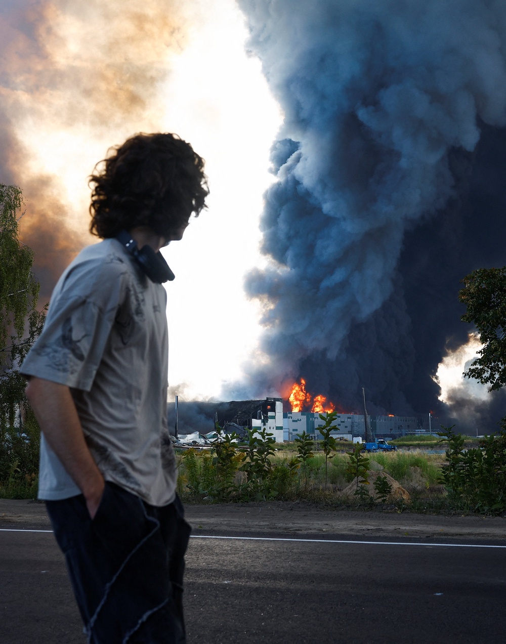 A man looks on as smoke rises over a warehouse, which was hit by a Russian drone strike, amid Russia's attack on Ukraine, in Kyiv region, Ukraine, August 27, 2026. (Reuters)