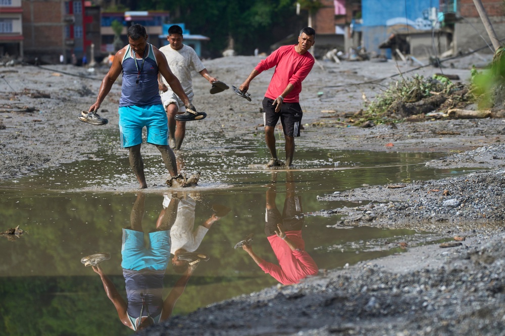 People walk through water in the aftermath of flash floods in Devighat in the Nuwakot district of Nepal (Niranjan Shrestha/AP) (AP)