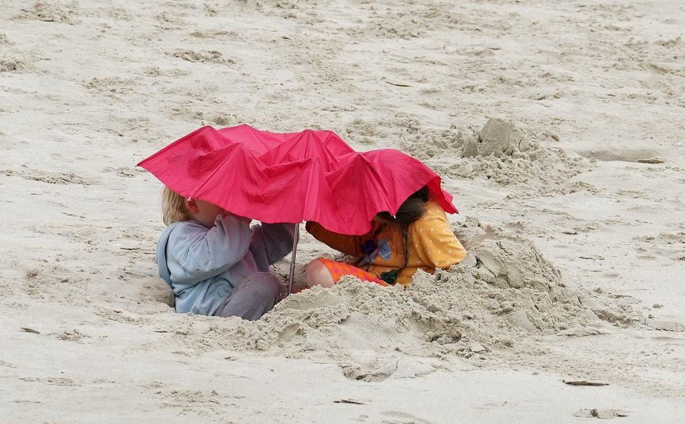 Children use an umbrella while playing on the beach in Folkestone, Kent (Gareth Fuller/PA) (PA Wire)