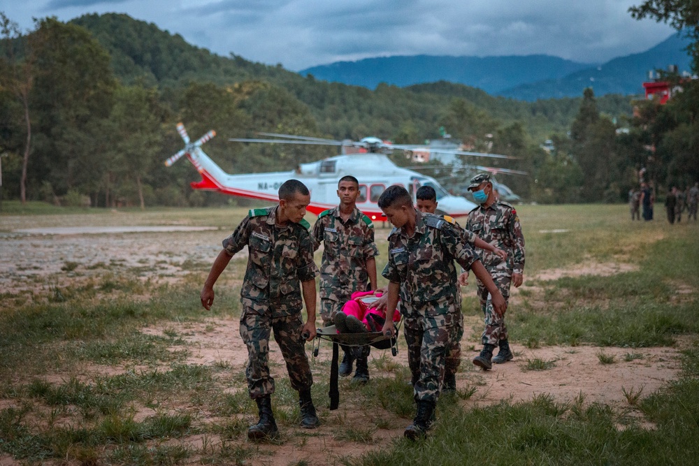 Soldiers carry a wounded resident airlifted by helicopter to a military camp (Getty)