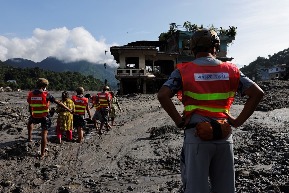 Rescuer help women to move through a muddy road following flash floods and a mudslide in Trishuli, Nuwakot district, Nepal, 28 August 2026 (Reuters)