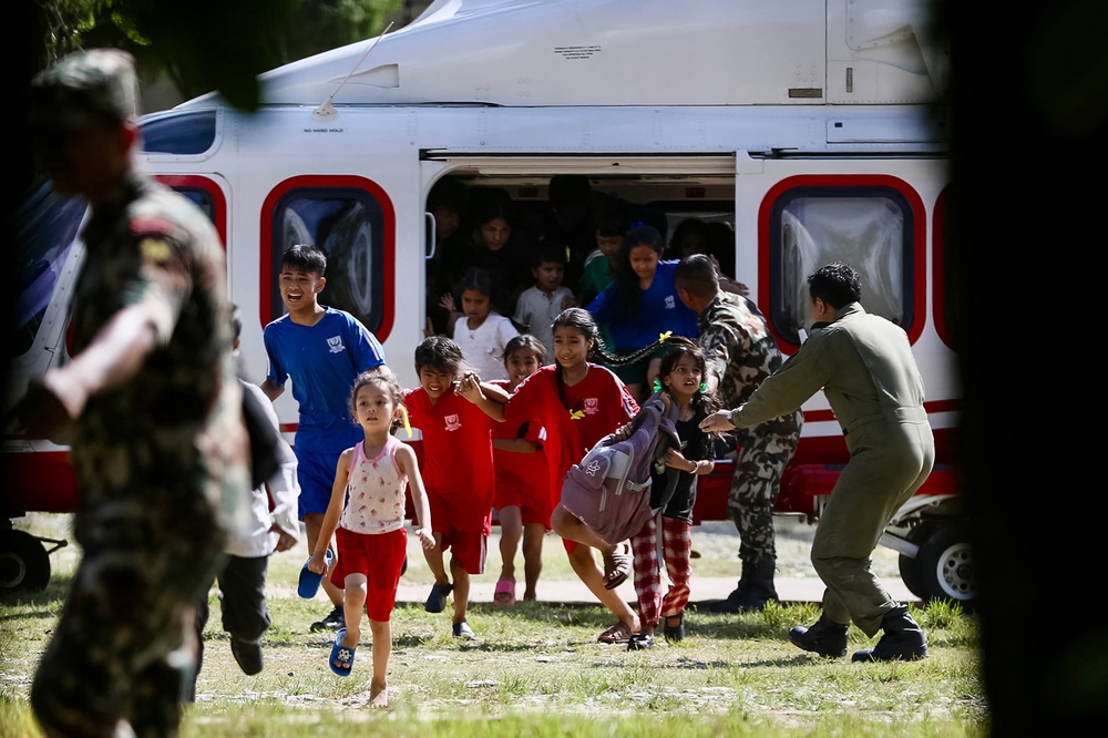 Rescued children disembark from a helicopter at an army camp following flash floods, in Battar Bazar town in Nepal's Nuwakot district on 28 August 2026 (AFP/Getty)