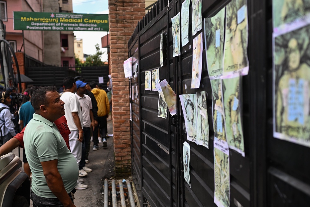 A man looks at images depicting victims of the recent flash floods on the gate of the morgue at the Maharajgunj Medical Campus (Getty)
