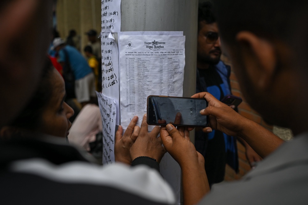 Family members of missing flood victims look at the list of missing flood victims at the emergency ward of the Maharajgunj Medical Campus, part of the Tribhuvan University Teaching Hospital (Getty)
