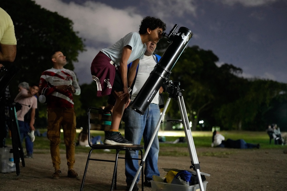 A boy looks at the moon through a telescope during a lunar eclipse in Caracas, Venezuela. (AP)