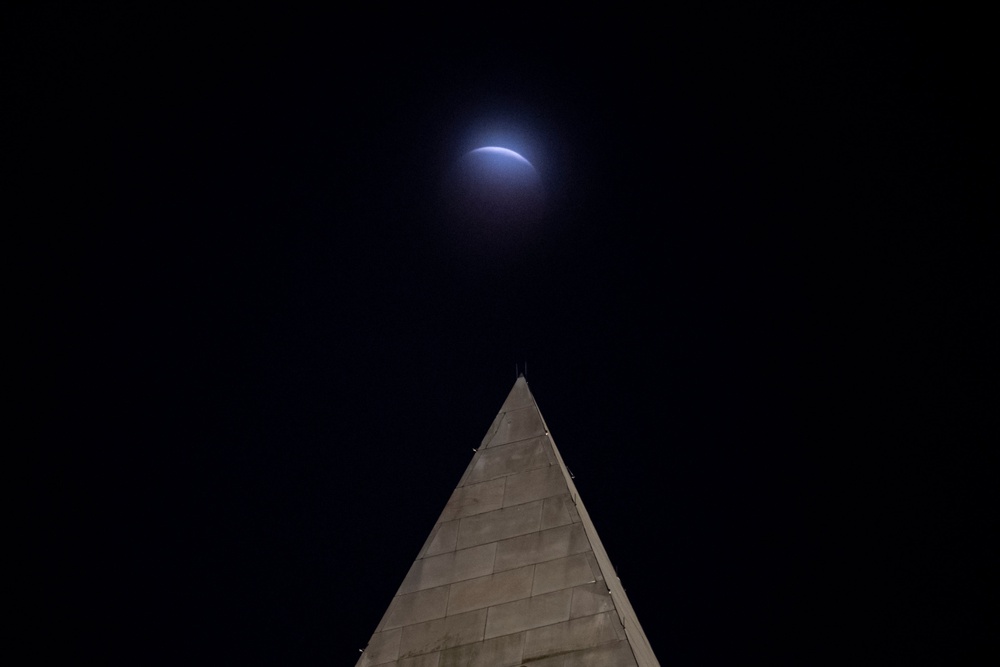 A lunar eclipse of the Moon is seen through clouds behind the Washington Monument. (AP)