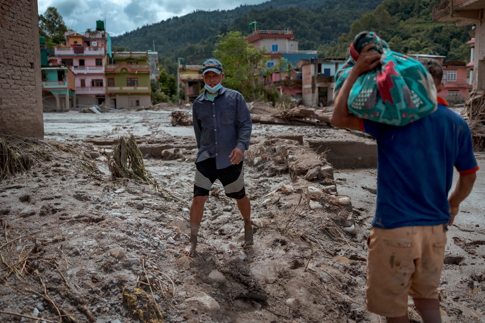 Residents walk along thick mud and debris following flash floods on 28 August 2026 in Devighat, Nepal (Getty)