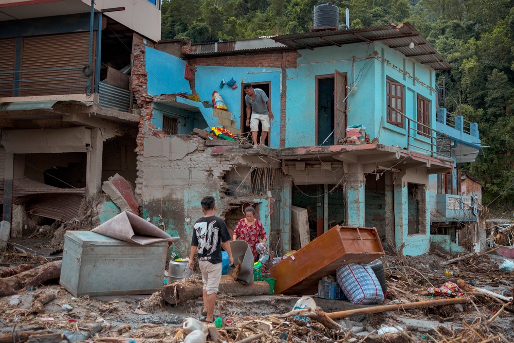 Residents salvage belongings from their destroyed home following flash floods (Getty)
