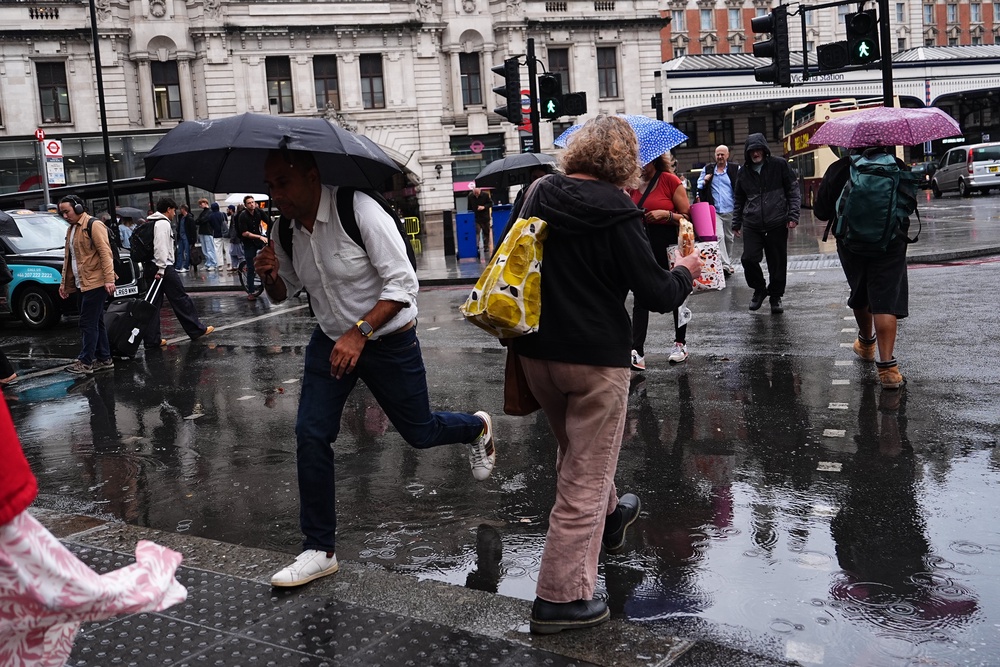 People walking in the rain near Victoria train station (PA) (PA Wire)