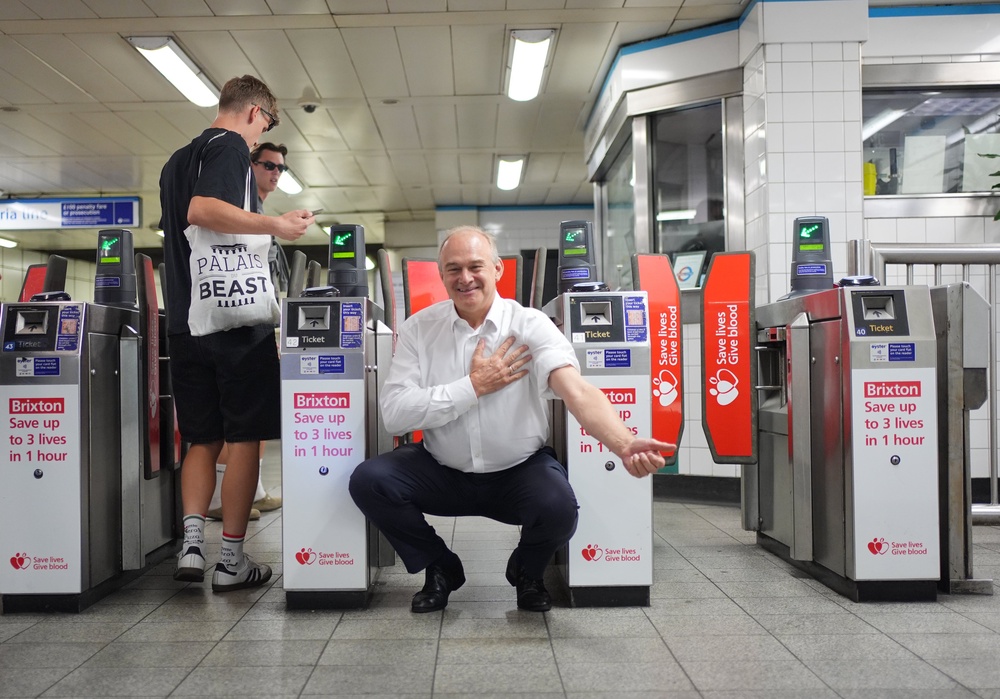 Sir Ed Davey with signage at Brixton underground station (Yui Mok/PA) (PA Wire)