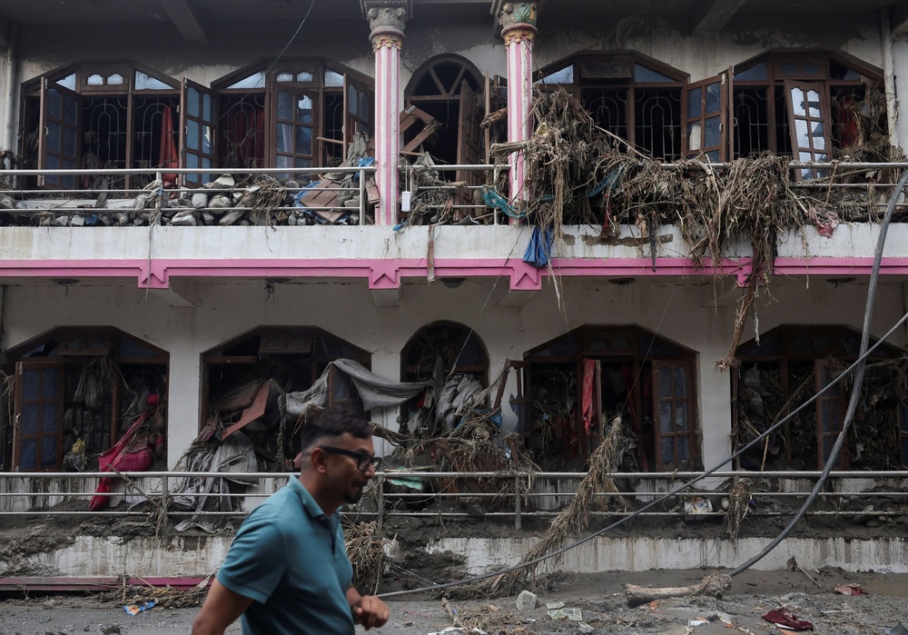 A man walks past a damaged house after flash floods and mudslide, at Devighat, Nuwakot district, Nepal (Reuters)