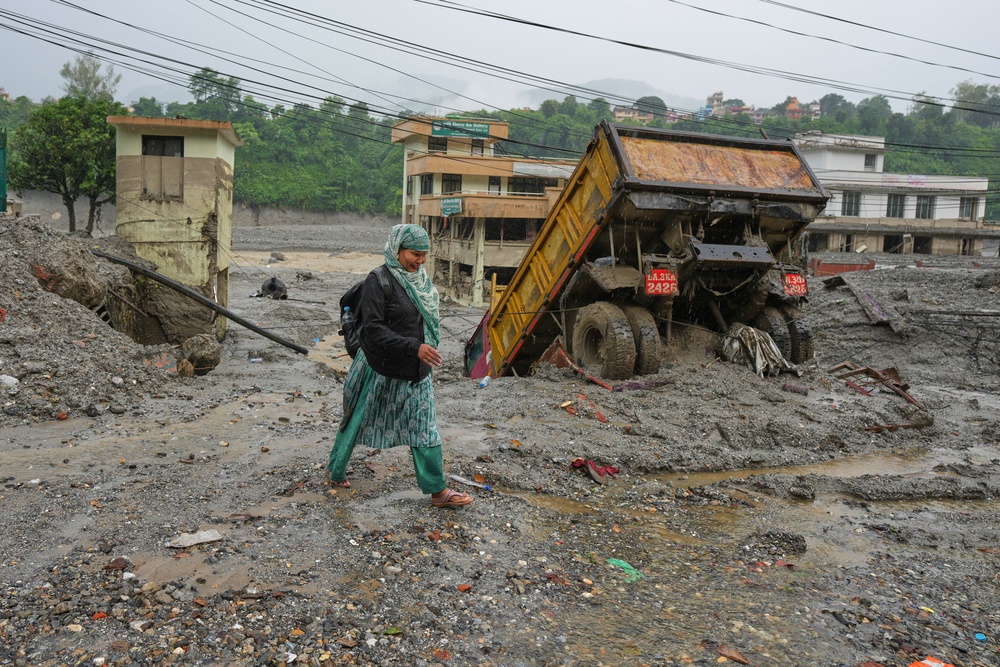 A woman walks through mud and debris left behind by flash flooding in Nepal’s Nuwakot district (Rajesh Kumar Singh/AP) (AP)
