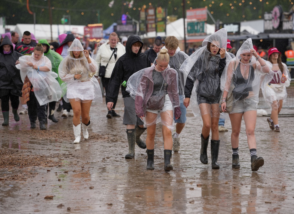 Festivalgoers shelter from the rain (Jeff Moore/PA) (PA Wire)