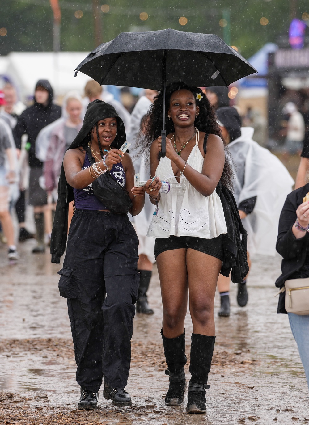 Festivalgoers shelter from the rain as they walk through the muddy site at the Reading Festival at Little John’s Farm, Reading, Berkshire (Jeff Moore/PA) (PA Wire)
