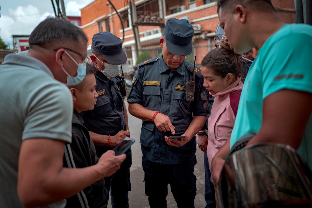 A woman inquires with police about her missing relative, outside Maharajgunj Medical Campus (Getty)
