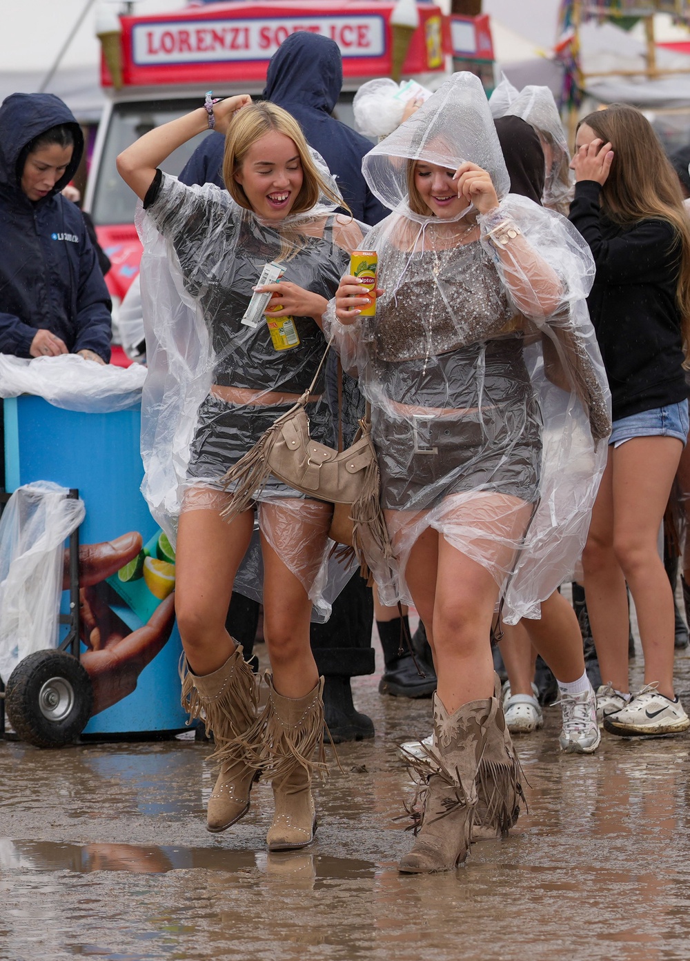Festivalgoers shelter from the rain in plastic ponchos as they walk through the muddy site at Reading Festival (Jeff Moore/PA) (PA Wire)