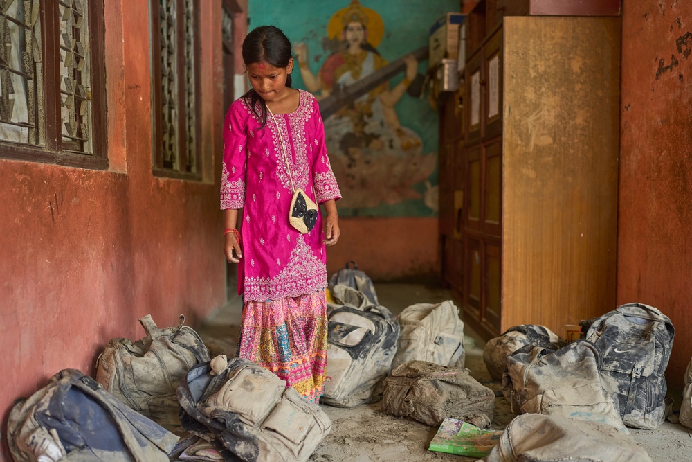A student from the school searches for her school bag from a pile extracted from the mud brought in by the recent flash floods (AP)