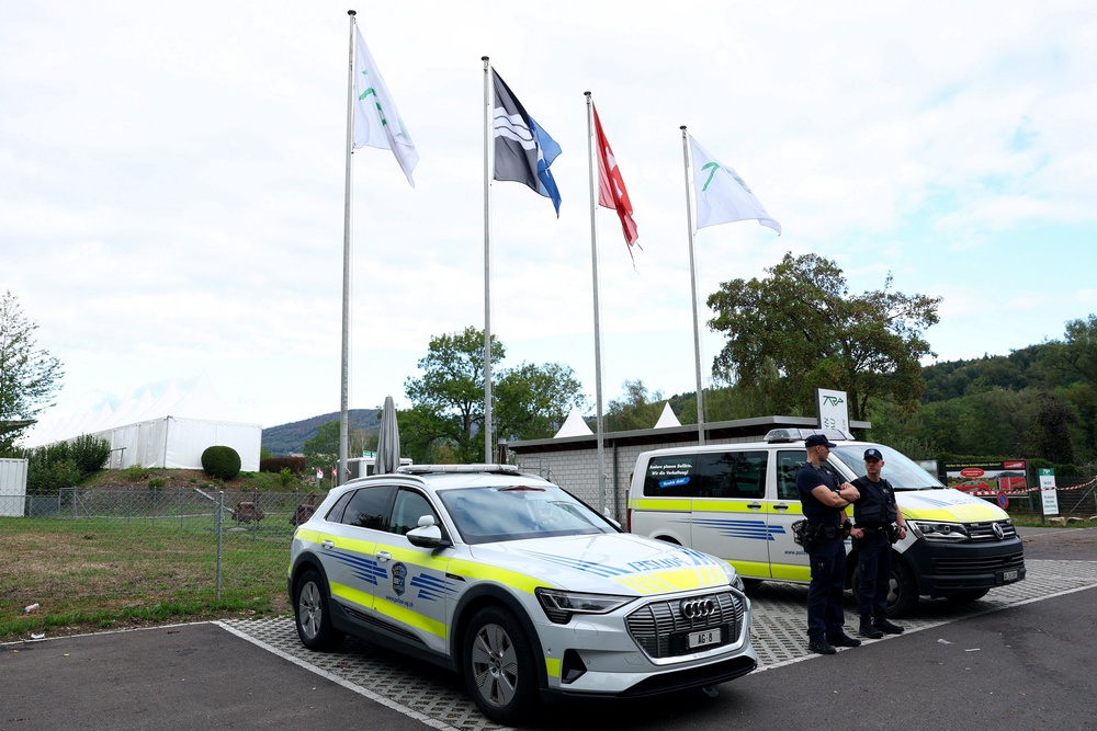 Police officers stand guard near the site of a rave party, following a deadly shooting incident at an event on Sunday, near the Schachen horse racing track, in Aarau (Reuters)