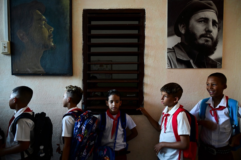 Students queue next to portraits of Cuban revolutionary leaders Argetine Ernesto Guevara and Fidel Castro (AFP/Getty)