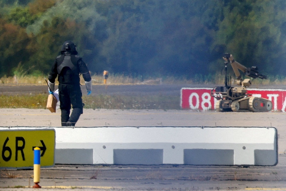File photo: A police officer in protective clothing walks next to an explosive-disarming robot (EOD) at Leipzig/Halle Airport in Schkeuditz, Germany (Reuters)