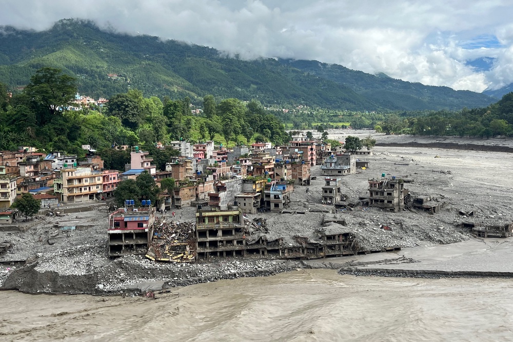 An aerial view shows a torrent of muddy water surging past houses and through the Trishuli River in the aftermath of flash floods at Trishuli Center in Nepal's Nuwakot district (AFP/Getty)