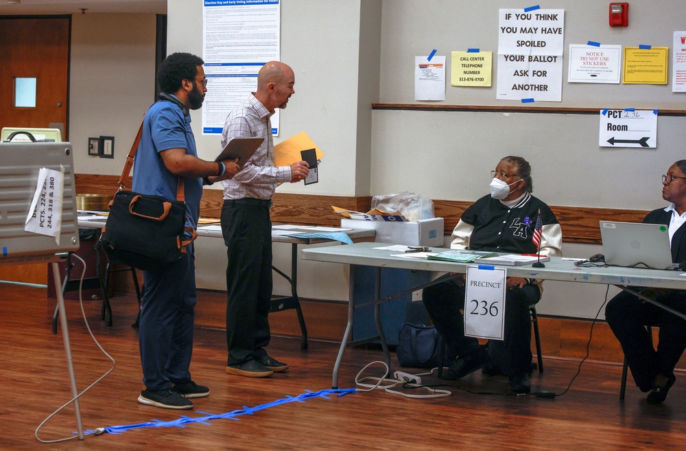 A poll monitor from the Department of Justice, seen flashing a badge to election workers in Detroit, is among hundreds of DOJ observers being deployed to polling locations this year (Reuters)