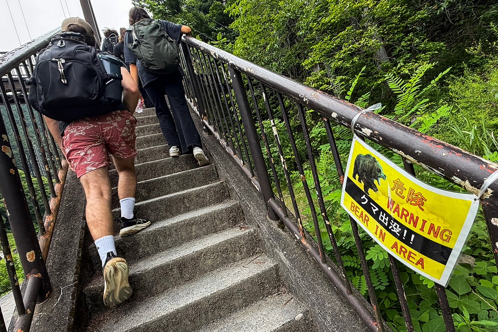 Hikers walk past a warning sign in Okutama on the outskirts of Tokyo on 14 June 2026 (AFP/Getty)